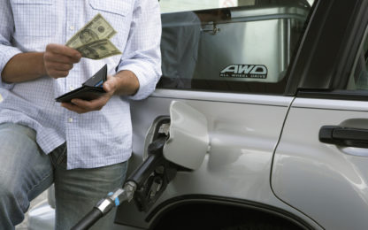 Man pumping gas into his car, and pulling money out of his wallet. Photo from Alpha Media USA Portland OR