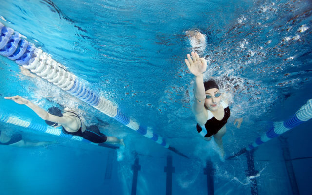 Underwater photo of two women swimming laps in a swimming pool. Photo by Alpha Media USA Portland OR