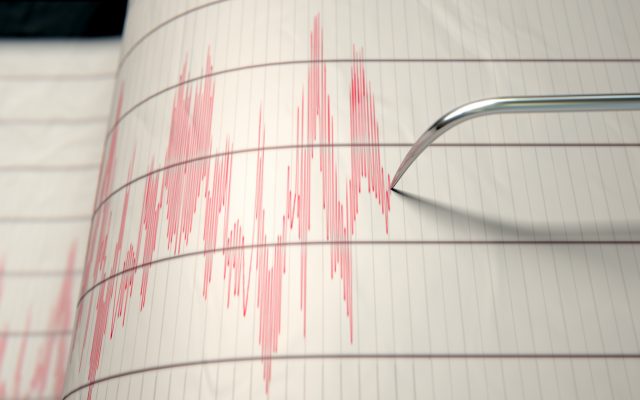 A closeup of a seismograph machine needle drawing a red line on graph paper depicting seismic and earthquake activity - 3D render. Photo from Alpha Media Portland OR