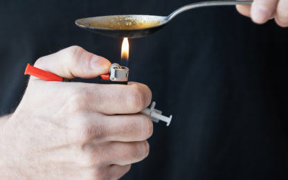 Close-up of man boiling heroin in spoon while holding a syringe in his hand. Photo from Alpha Media Portland OR