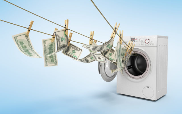 Money attached to a clothesline with clothespins, coming out of an electric dryer. Photo from Alpha Media Portland OR