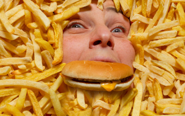 Woman with face covered by french fries and cheeseburger. Photo from Alpha Media Portland OR