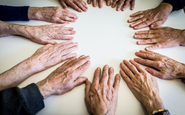 Elderly people making circle of hands. Photo from Alpha Media Portland OR