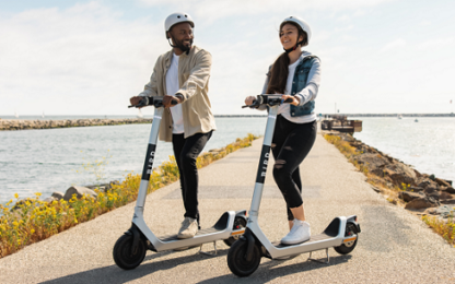 Photo of two people on Bird e-scooters on a waterfront walkway. Photo from Bird Scooters and City of Indio CA